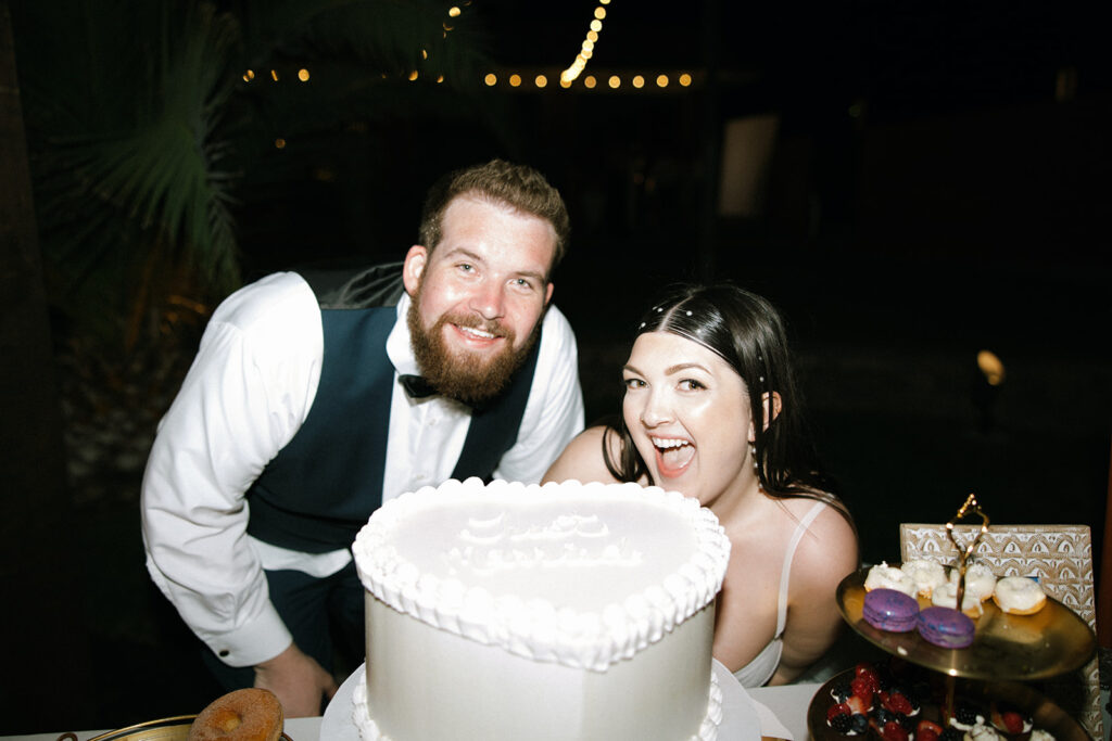 Bride and groom posing with wedding cake